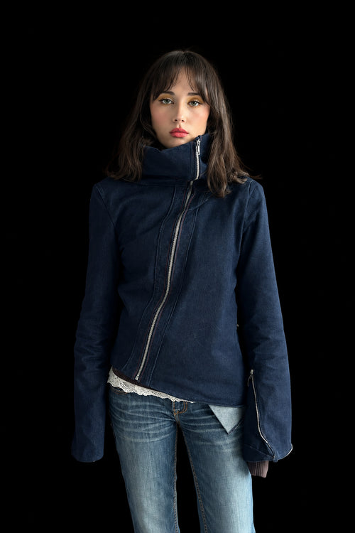 Person wearing a blue jacket and jeans standing against a red wall.