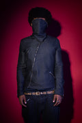 Person wearing a dark jacket and pants with a hood against a red background